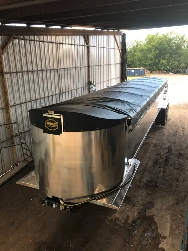Covered metal livestock feeder inside a barn.