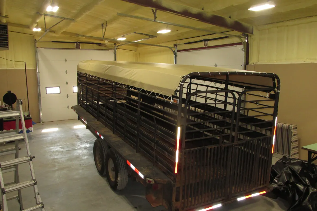 A livestock trailer parked inside a barn or garage.