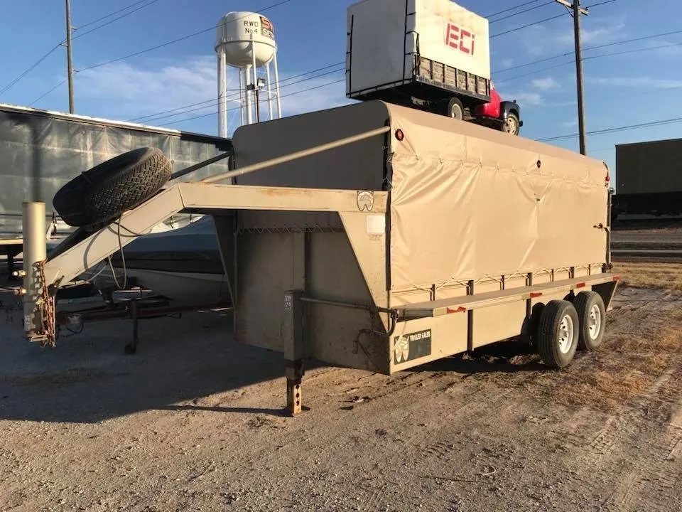 Covered trailer parked outdoors near a water tower.