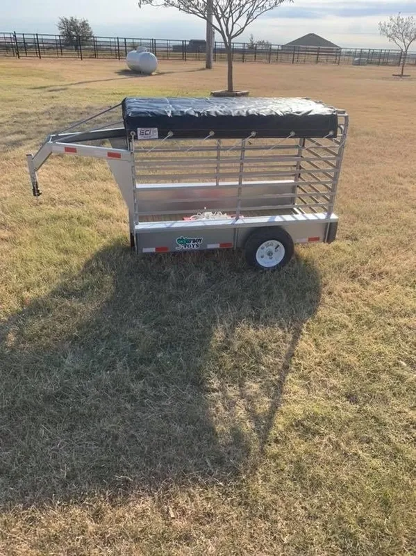 A small metal trailer with a canopy on an open field.
