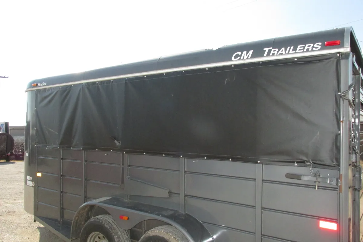 Black GM trailer with covered top parked outdoors.