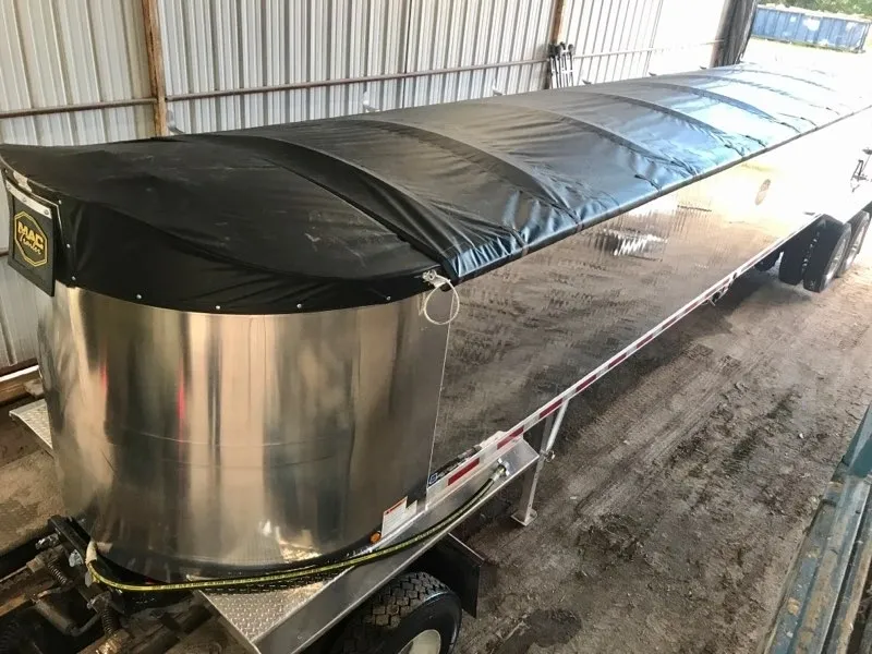 A long metal container with a black cover inside a warehouse.