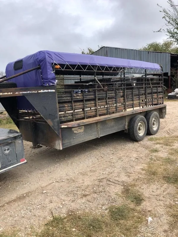 A purple-covered livestock trailer parked on a dirt path.