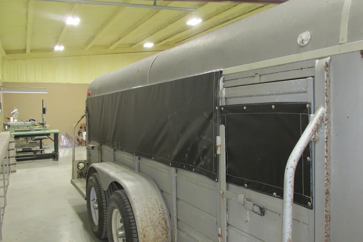 A covered trailer parked indoors with dual wheels.