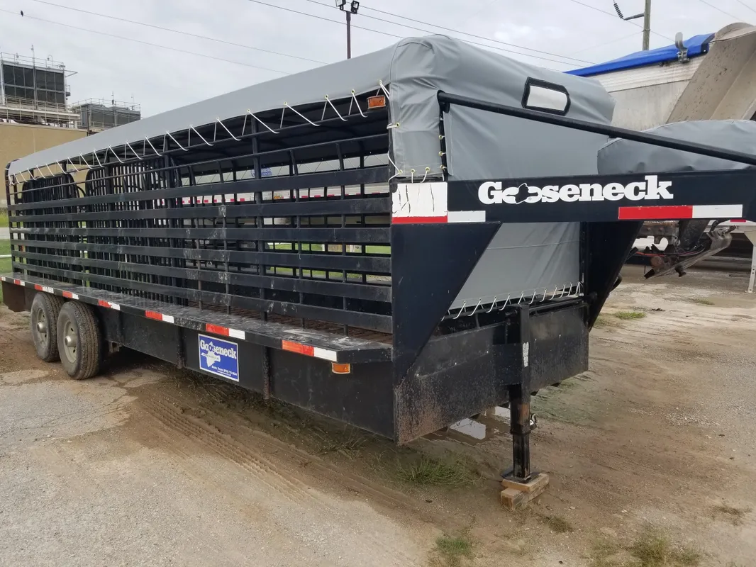 Black livestock trailer parked on a dirt surface.