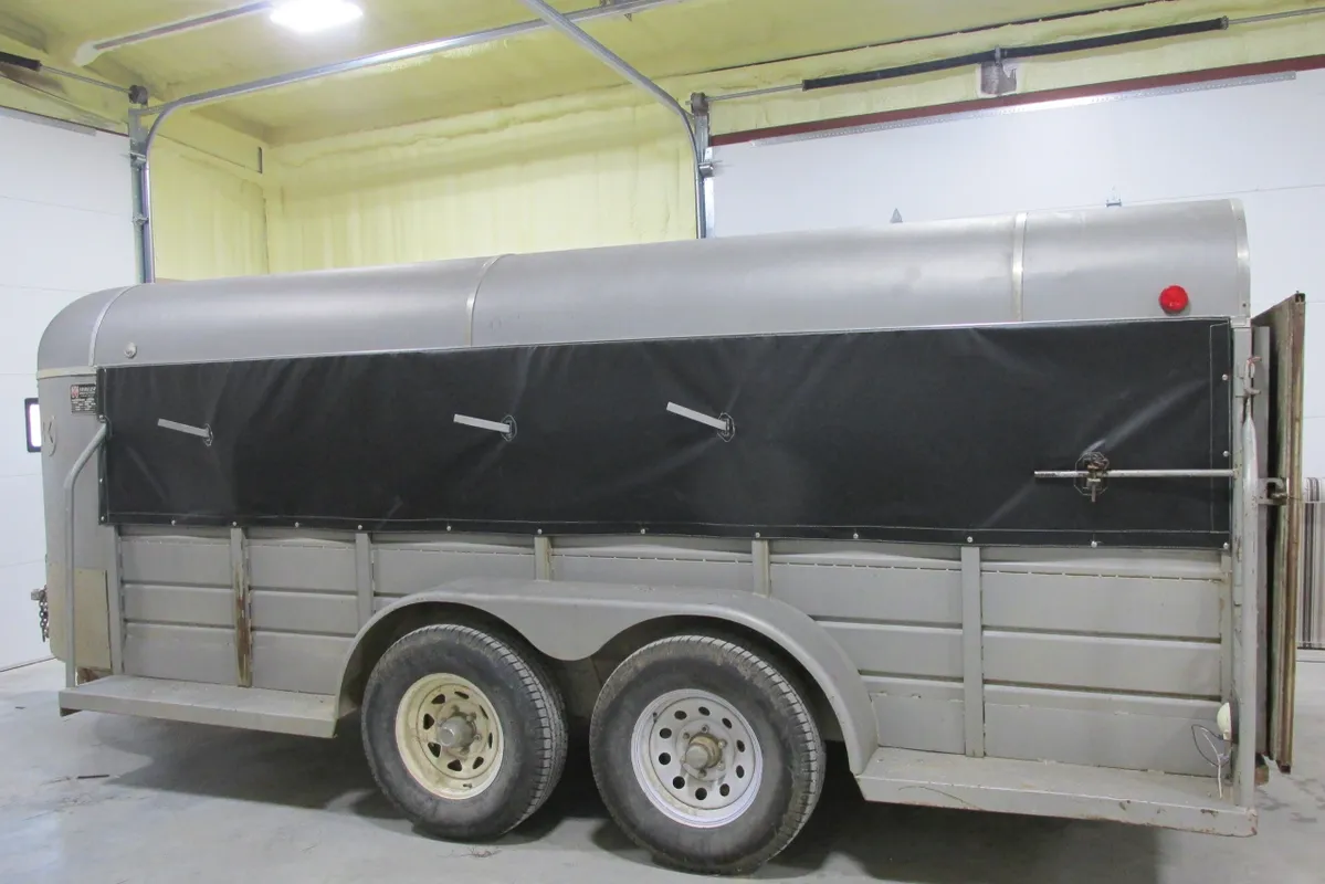 A covered trailer with dual axles parked indoors.