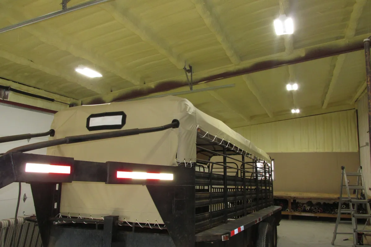Large livestock trailer with metal bars inside a warehouse.