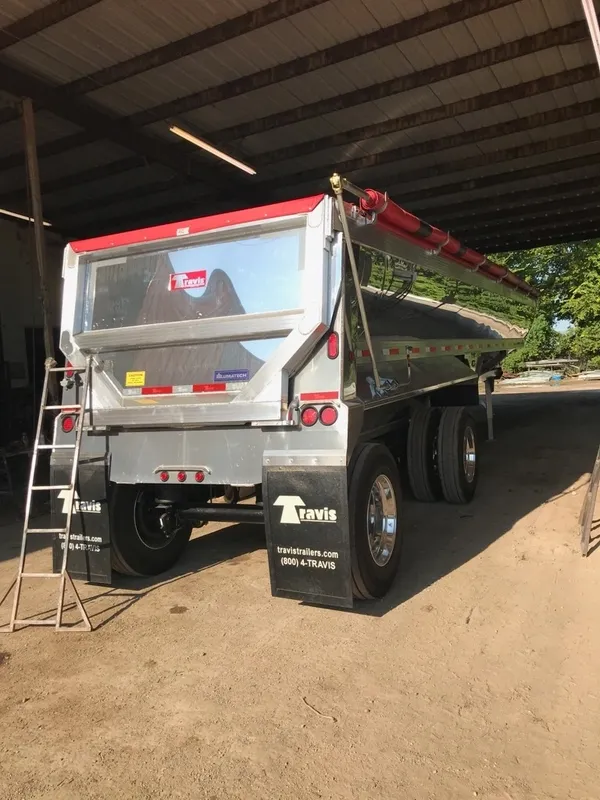 Shiny silver tanker trailer parked indoors with a ladder beside it.