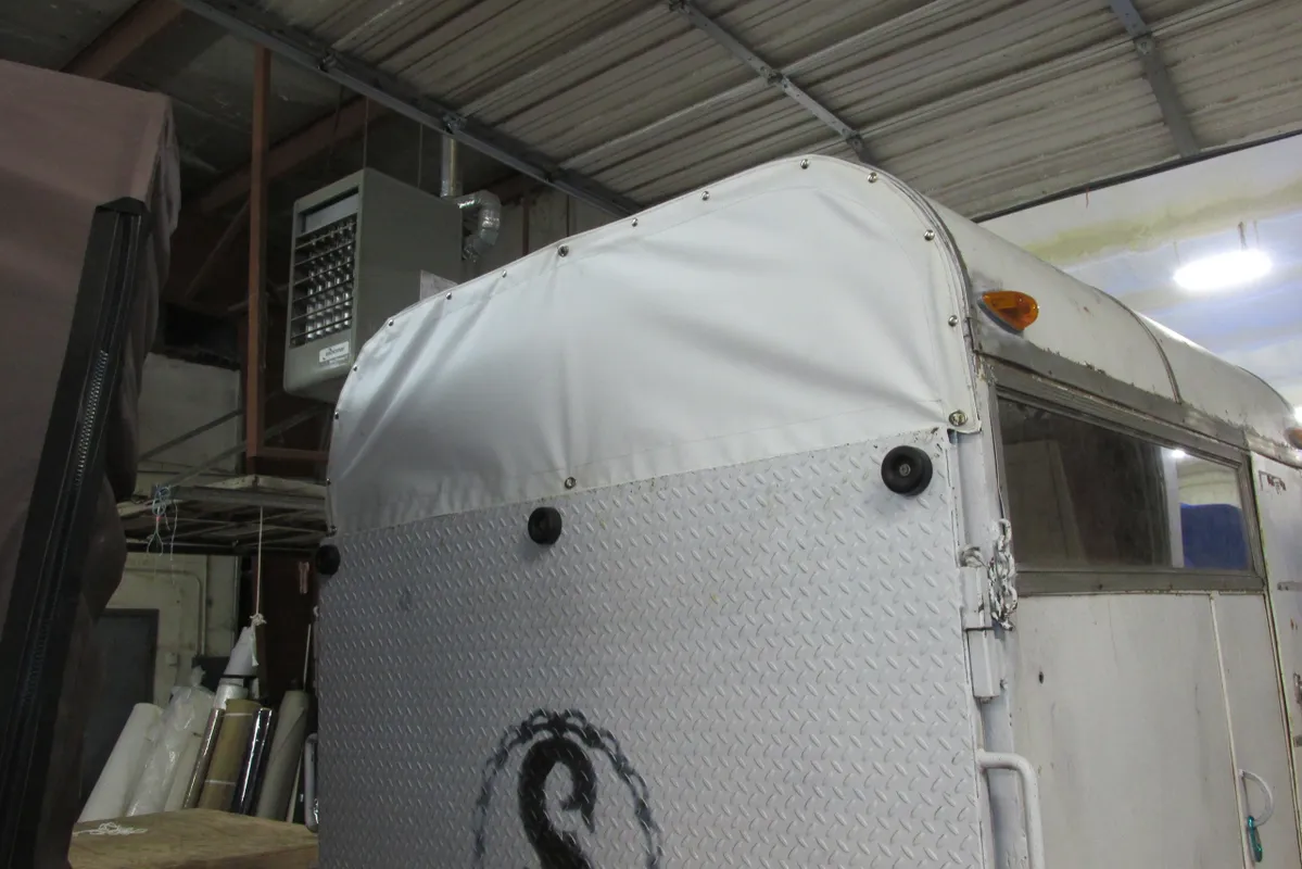White padded truck trailer cover with ventilation holes and a logo.
