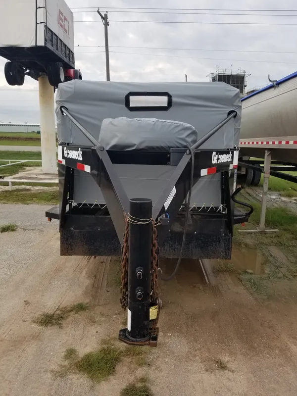 Front view of a large black trailer hitch on a dirt ground.