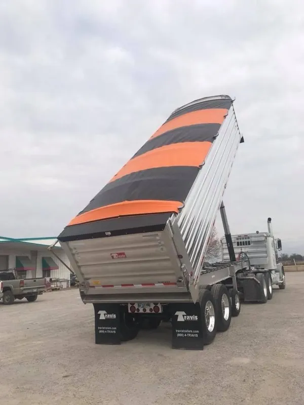 Truck with a tilted cargo container featuring orange and black stripes.
