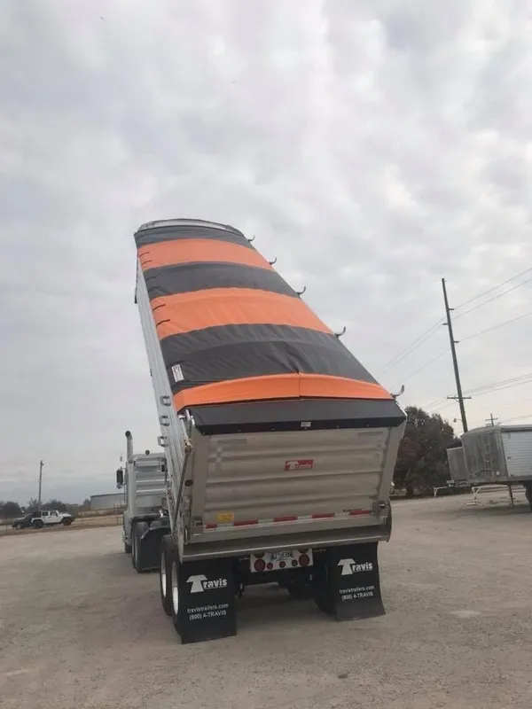 A truck with an oddly bent orange and black striped tarp cover.