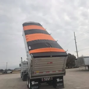 Truck with a large striped sail-like cover on its cargo area.